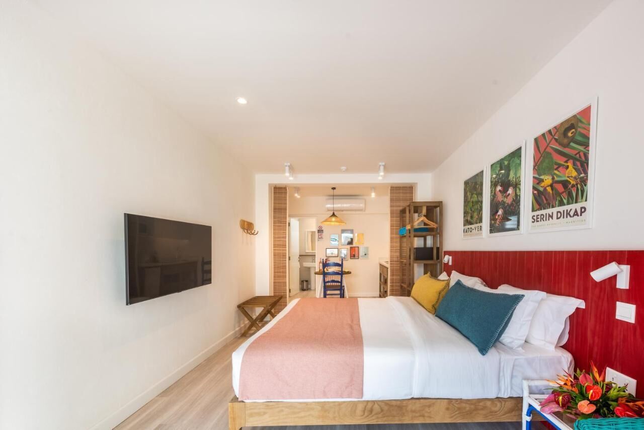 A modern hotel room with a large bed, a TV mounted on the wall, and a small desk area.