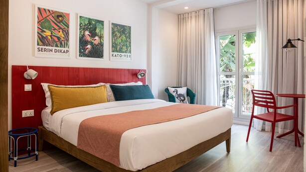 A modern hotel room with a large bed, red headboard, and artwork on the wall. - Dodo Square (Grand-Baie)