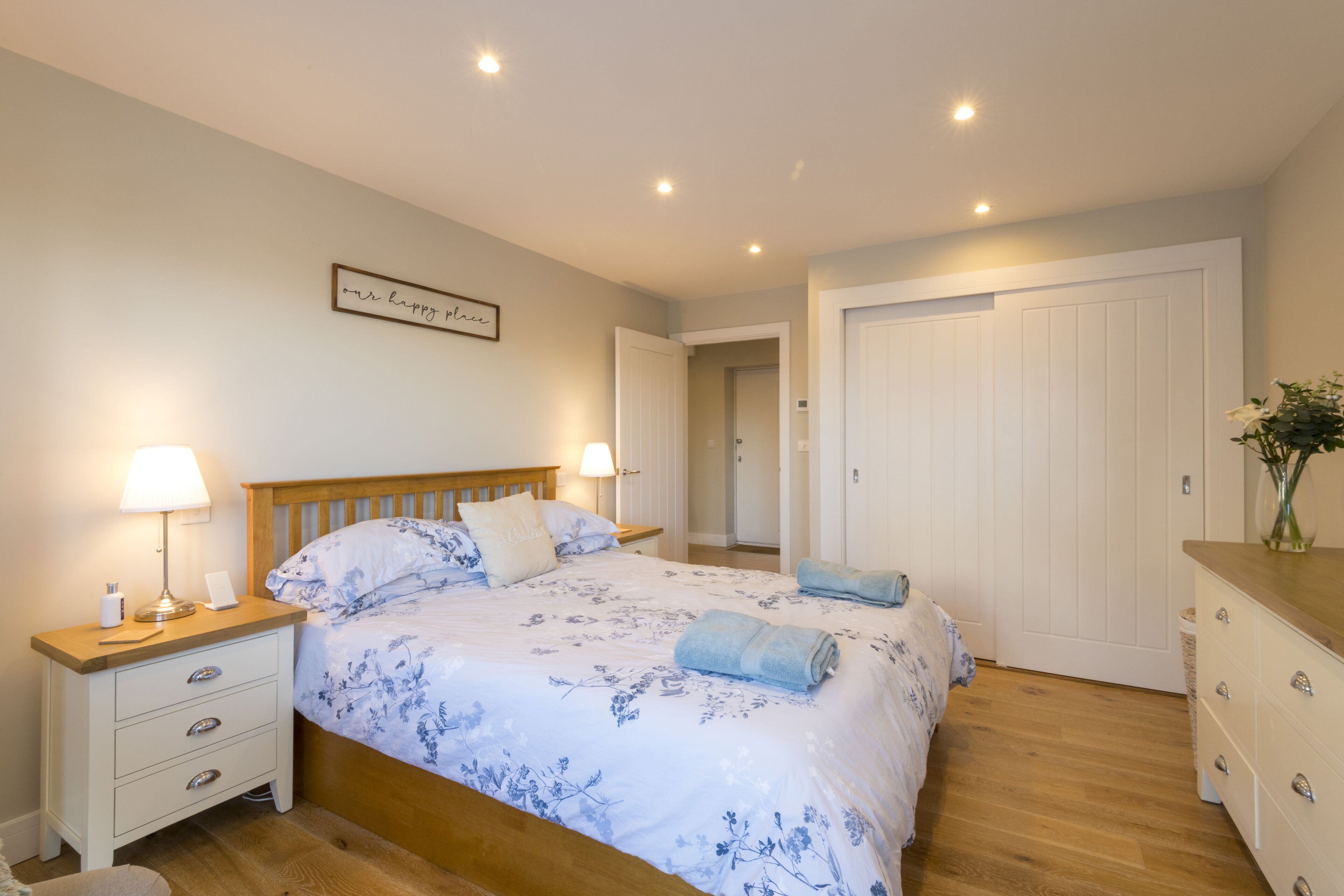A bedroom with a bed, nightstands, a dresser, and a door.