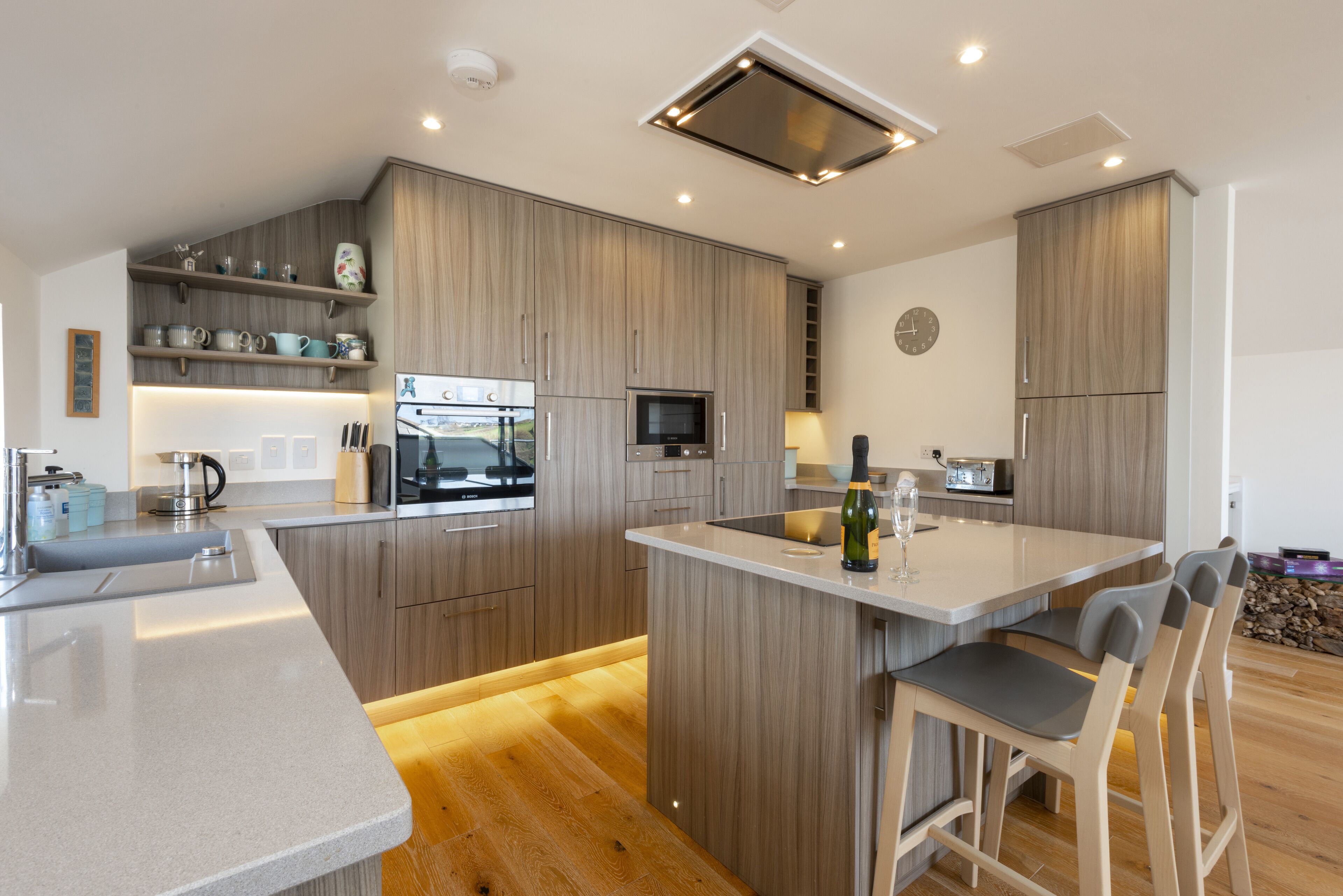 Une cuisine moderne avec des meubles en bois, un îlot central et des tabourets de bar.