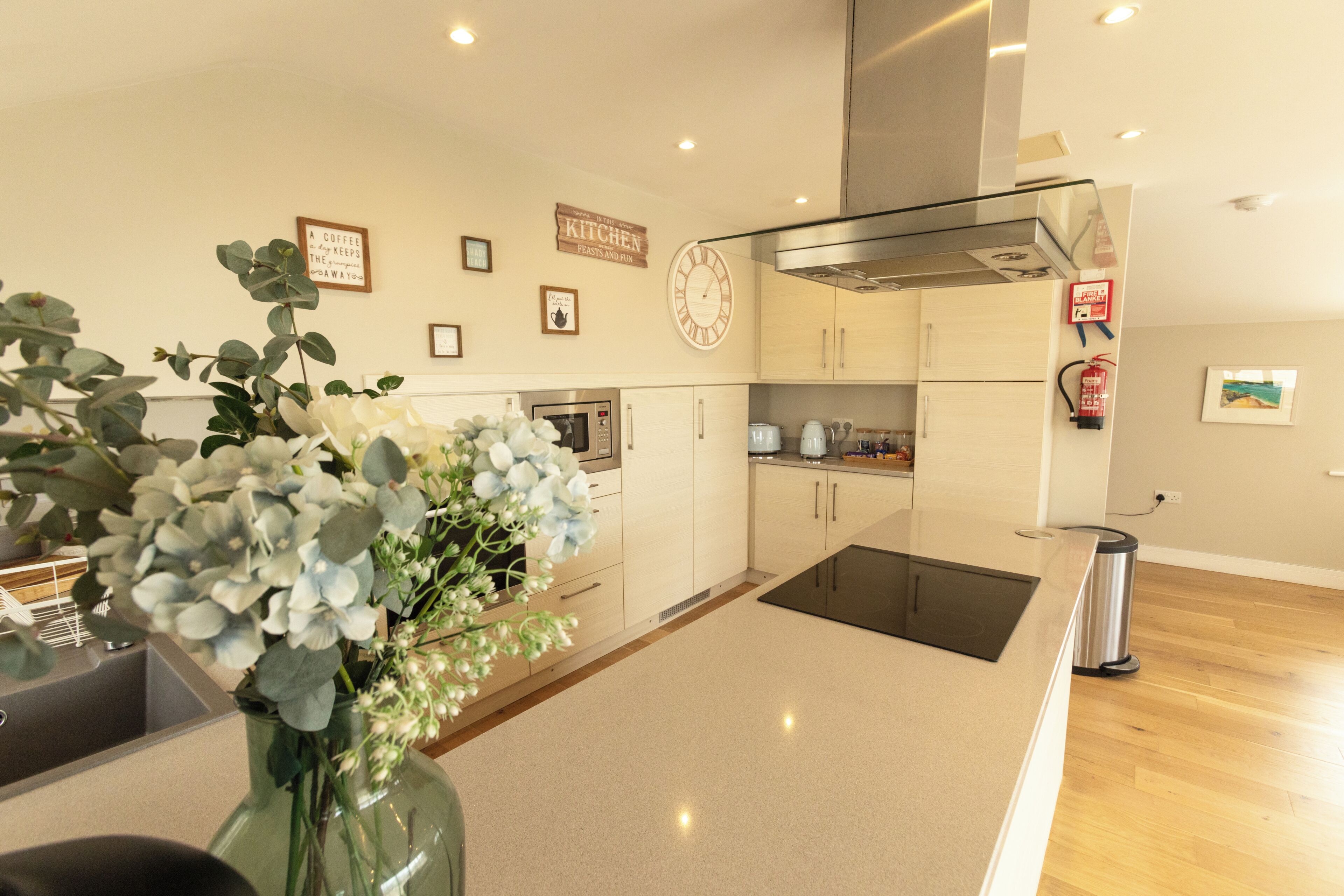 A modern kitchen with a central island, stainless steel appliances, and a clock on the wall.
