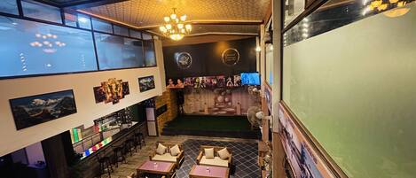 A restaurant with a high ceiling, patterned ceiling, and a bar area with stools and a counter.