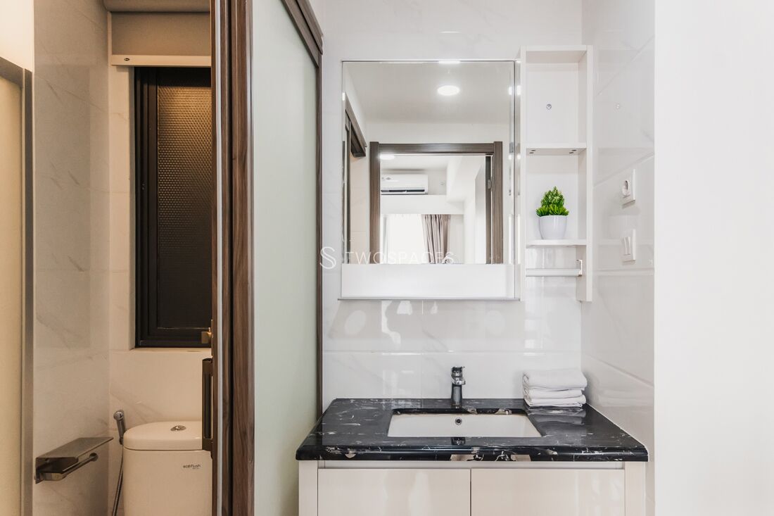 A modern bathroom with a black sink, white cabinets, and a mirror above the sink.
