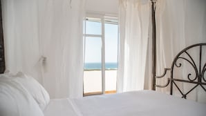 Une chambre à coucher avec un lit, des rideaux blancs et une vue sur la plage.