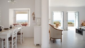 Un vaste espace de vie avec vue sur la mer, un coin repas avec une table et des chaises, et une cuisine moderne.