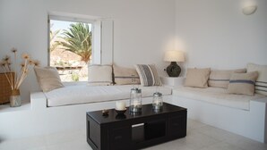 Un salon moderne avec un canapé blanc, une table basse noire et une lampe.