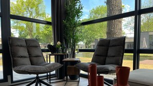 A modern room with two dark leather chairs, a small wooden table, and three red vases on a wooden table. - Ferienhaus Holland-cube Direkt am Veluvemeer in Bad Hoophuizen (Hulshorst)