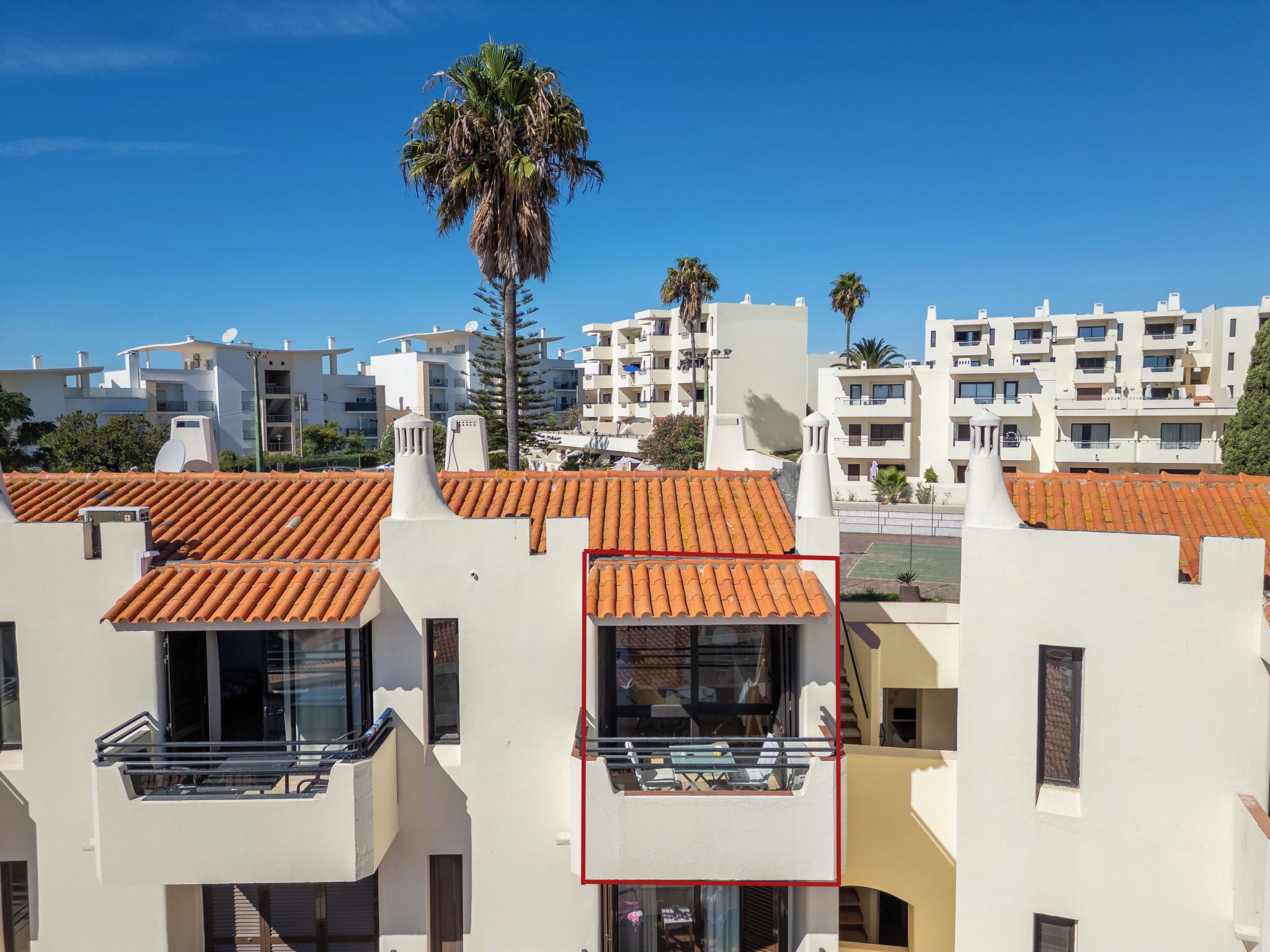 Un quartier résidentiel avec des immeubles modernes, des toits recouverts de tuiles rouges et un ciel d’un bleu éclatant.