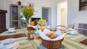 Un coin repas avec une table mise pour le petit-déjeuner, comprenant du pain, des fruits et un pot de miel.