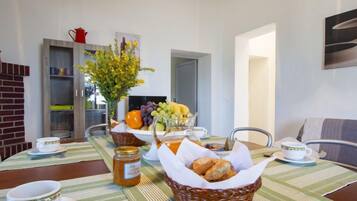 A dining area with a table set for breakfast, including bread, fruit, and a jar of honey.