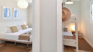 Un dormitorio con una cama doble, una cama individual y una mesita de noche.