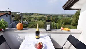 A balcony with a table set for two, featuring a bottle of champagne, a pomegranate, and a plate of oranges. - Comfortable Apartment with Attic in a Peaceful Village (Umag)