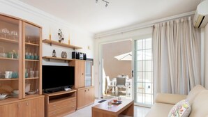A modern living room with a flat-screen TV, wooden cabinets, a sofa, and a dining area with a table and chairs. - El Faro by Interhome (Palm- Mar)