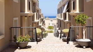 A corridor with potted plants and a view of the sea. - El Faro by Interhome (Palm- Mar)