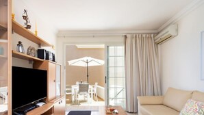 A modern living room with a flat-screen TV, wooden furniture, a sofa, and a dining area with a table and chairs. - El Faro by Interhome (Palm- Mar)