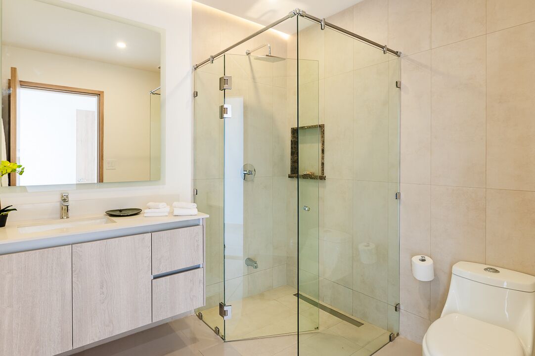A modern bathroom with a glass-enclosed shower, a large mirror, and a toilet.