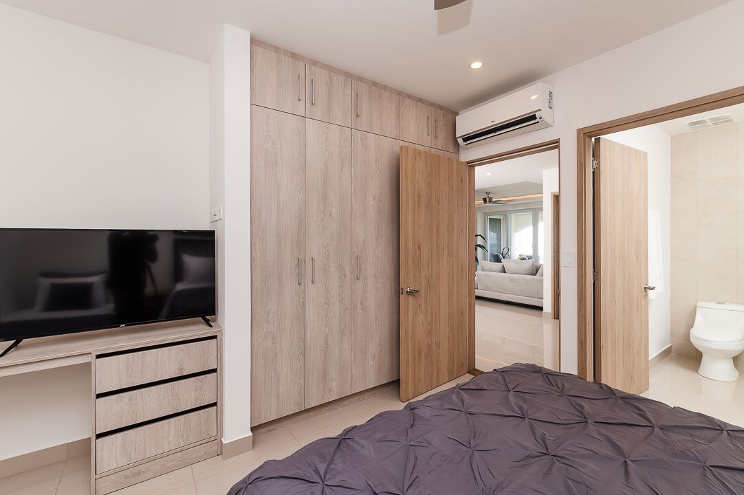 Camera da letto moderna con letto, televisore, armadio e condizionatore d'aria.