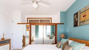 A bedroom with a bed, a dresser, a ceiling fan, and a view through a sliding door.