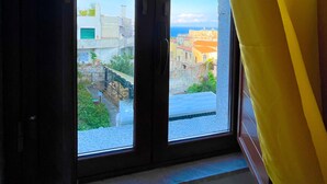 A window with a view of a cityscape, curtains partially drawn, and a glimpse of the interior. - Panoramic Taormina Center (Taormina)