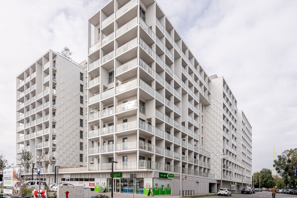 A multi-story building with a grid-like facade, balconies, and ground-level commercial spaces.