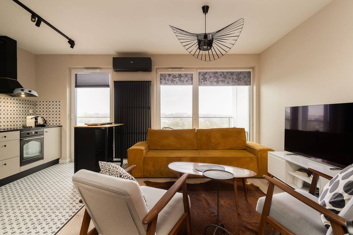 A modern living room with a sofa, TV, and a dining area.