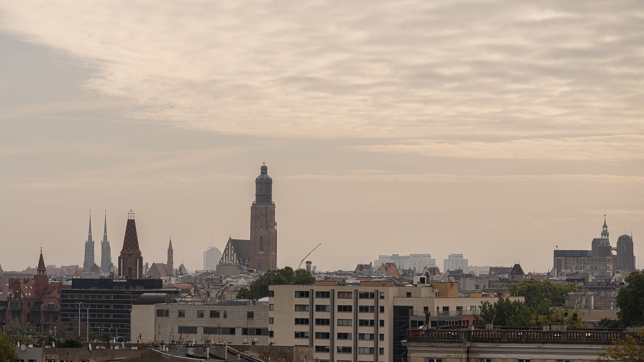 A cityscape with various buildings, including a prominent tower and several spires.