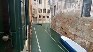 Un canal estrecho con un barco amarrado a la derecha, flanqueado por edificios antiguos con múltiples ventanas y balcones.
