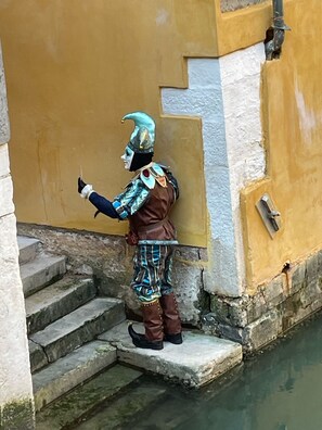 A statue of a person in historical costume standing on stone steps next to a body of water. - Wake Up to Gondolas! Venetian Home with Canal View (Venezia)