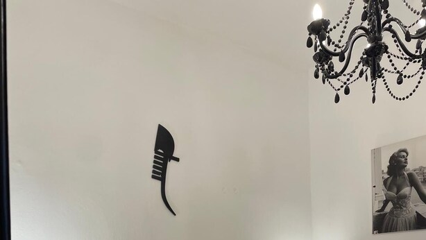 Un dormitorio con dos camas, una araña, un cuadro en la pared y una lámpara de noche.