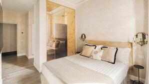 A modern bedroom with a large bed, a walk-in closet, and a glass shower enclosure. - Luxury apartment in Trastevere (Roma)