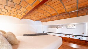 A bedroom with a brick ceiling, a white bed, a wooden floor, and a mirror with string lights. - Best Location in Sayulita - Walk to Everything (Sayulita)