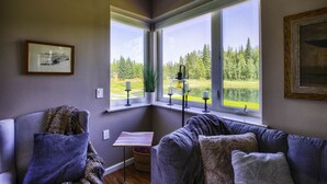 Ein Eckzimmer mit großem Fenster, einem kleinen Tisch und einer Couch.