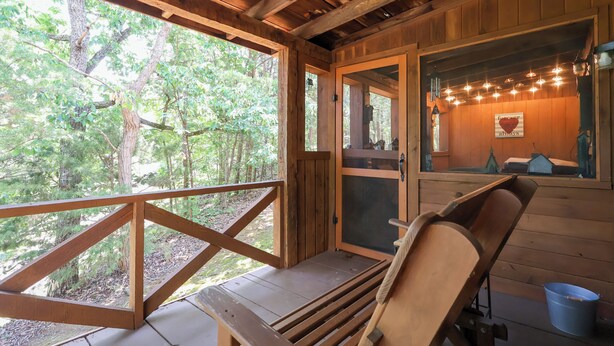 Une cabane en bois avec une terrasse, un banc et une vue sur la forêt.