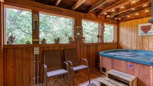 Une cabane en bois avec un bain à remous, deux chaises et un banc.