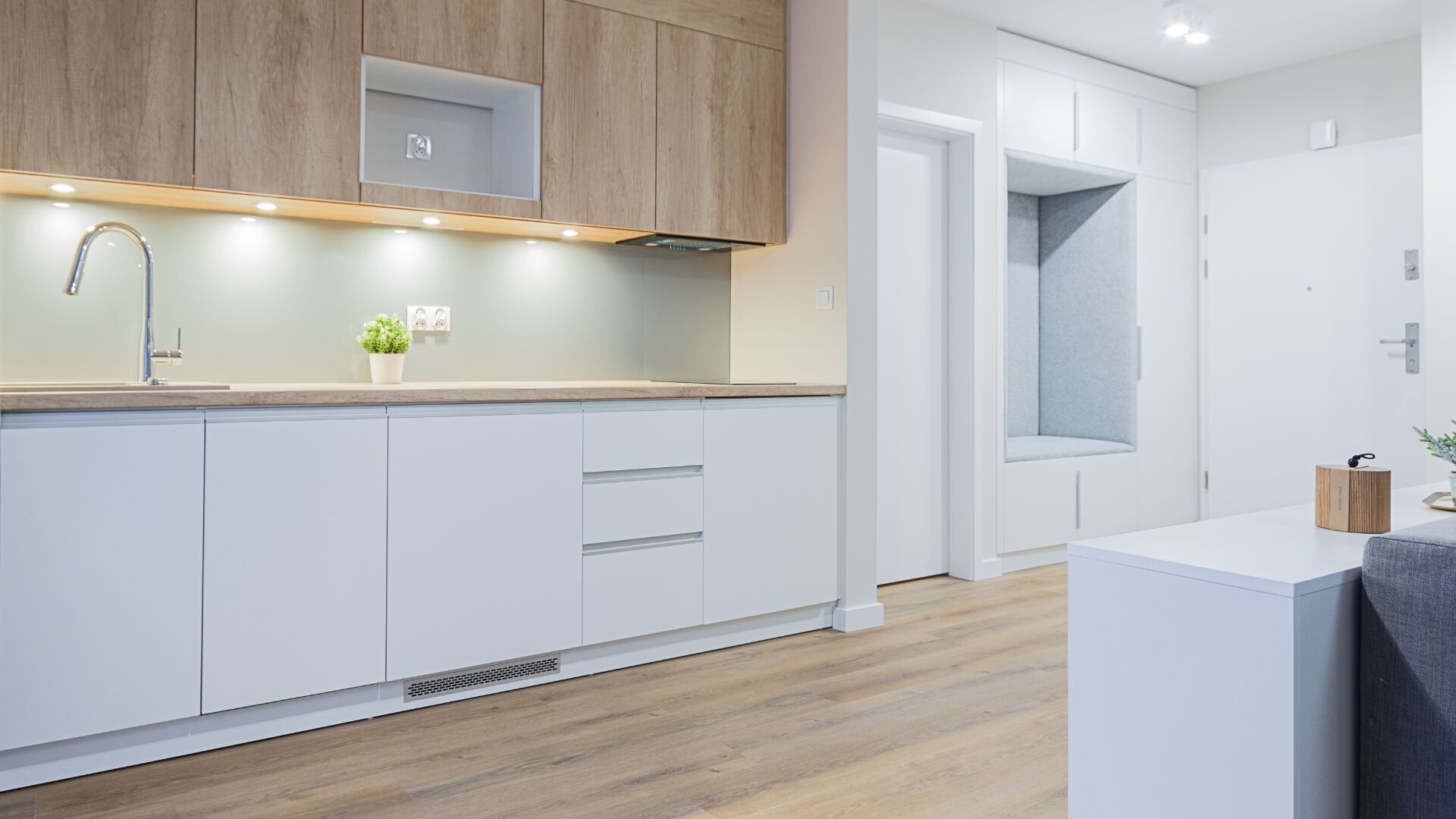 A modern kitchen with white cabinets, a wooden countertop, and a built-in stove.