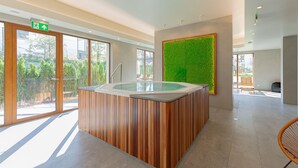 Een moderne spa-ruimte met een houten receptiebalie, een whirlpool en een groene wand.