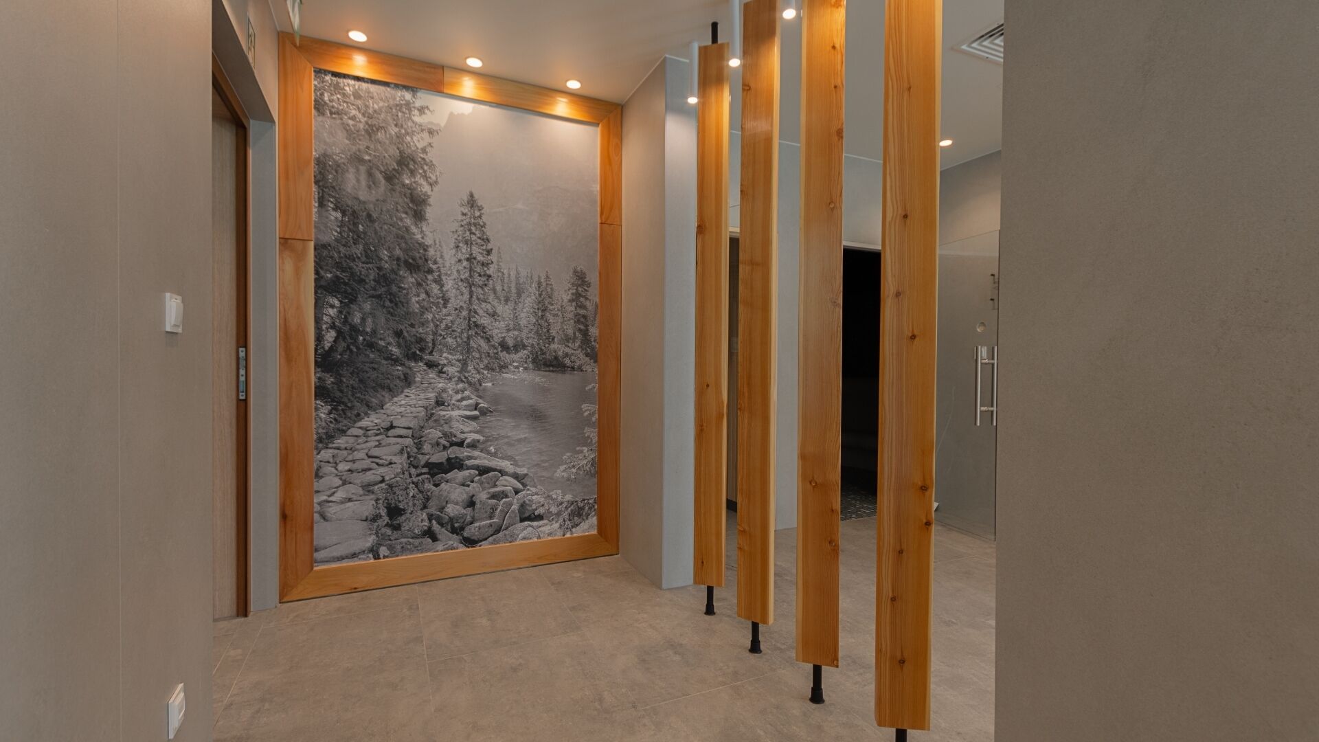 A hallway with a large wall mural of a snowy forest scene, wooden slats on the right, and a door at the end.