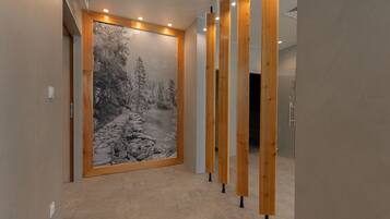 A hallway with a large wall mural of a snowy forest scene, wooden slats on the right, and a door at the end.