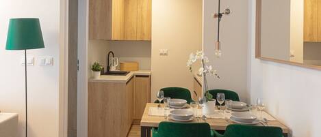 Una cocina moderna con armarios de madera, una mesa de comedor para cuatro personas y una lámpara de pie verde.