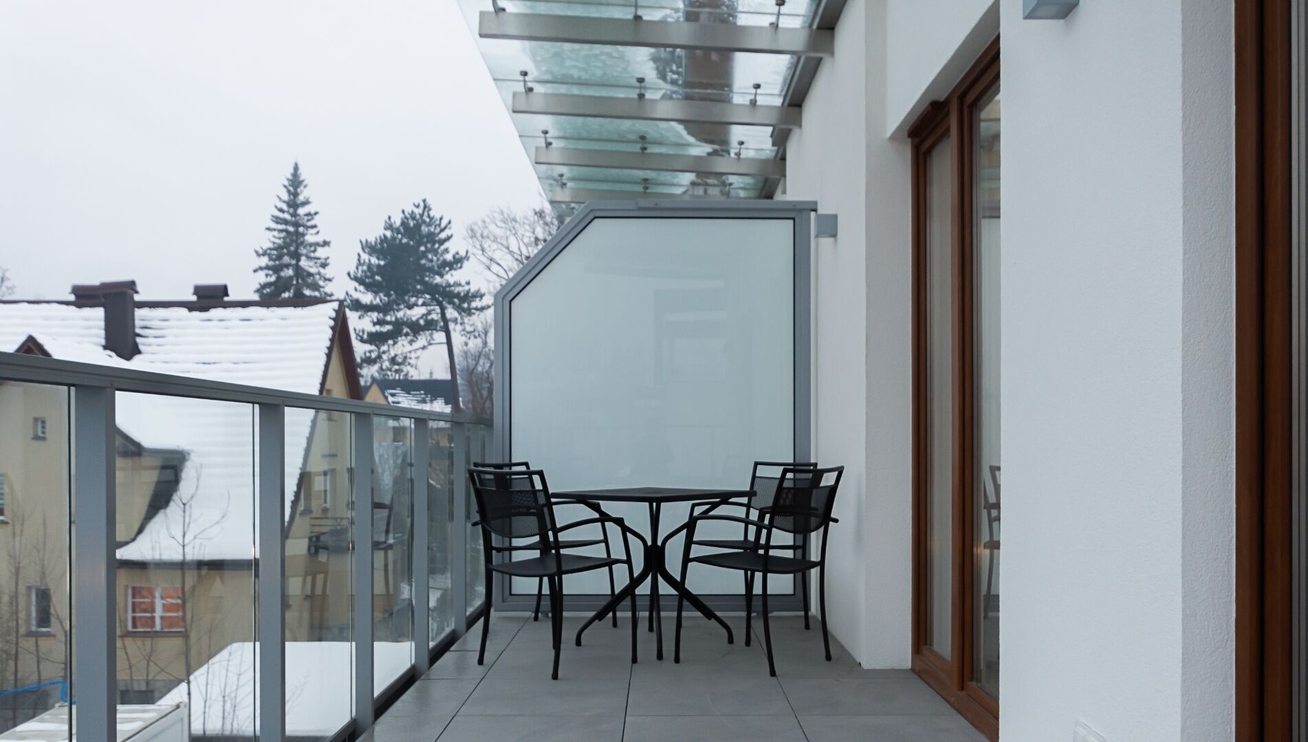 A balcony with a glass enclosure, a table, and four chairs.