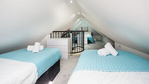 A bedroom with two beds, a staircase, and a small bathroom.