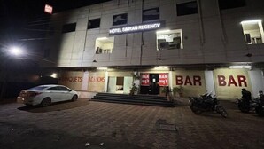 Un hôtel avec une enseigne indiquant « HÔTEL SIRAN REGENCY ». On y trouve plusieurs bars au rez-de-chaussée, et une voiture blanche est garée devant.