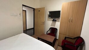 Une chambre d’hôtel équipée d’un lit, d’un bureau, d’une chaise, d’un téléviseur fixé au mur et d’une armoire.