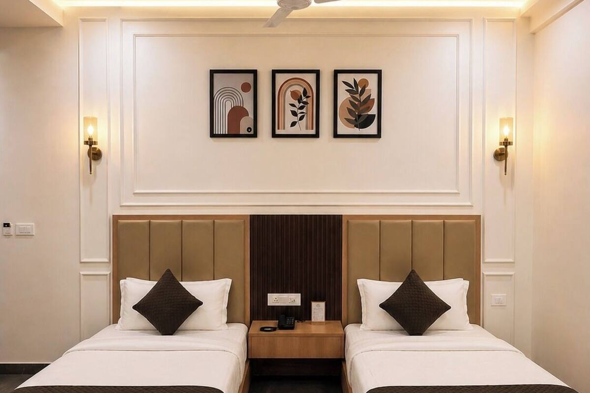 A hotel room with two beds, a ceiling fan, wall-mounted artwork, and a central nightstand.