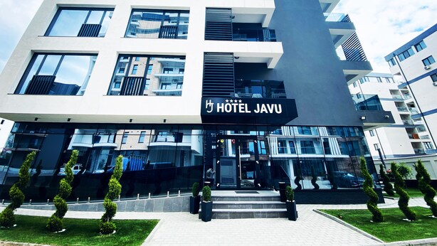 Un moderno edificio de hotel con una entrada destacada y un letrero que dice "HOTEL JAVU".
