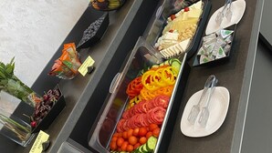Un bufé con diversas opciones de comida, entre ellas frutas, verduras y carnes.