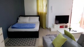 A bedroom with a bed, a TV, a small table, and a sofa. - Cheb's House (Abidjan)