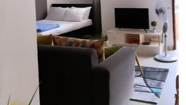 A bedroom with a bed, a desk with a computer, and a TV. - Cheb's House (Abidjan)