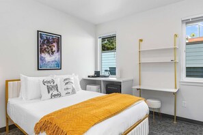 Una habitación de hotel con cama, escritorio, ventana y estante en la pared.