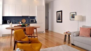 Un espace de vie moderne comprenant une cuisine, un coin repas et un coin salon confortable avec un canapé et des fauteuils.